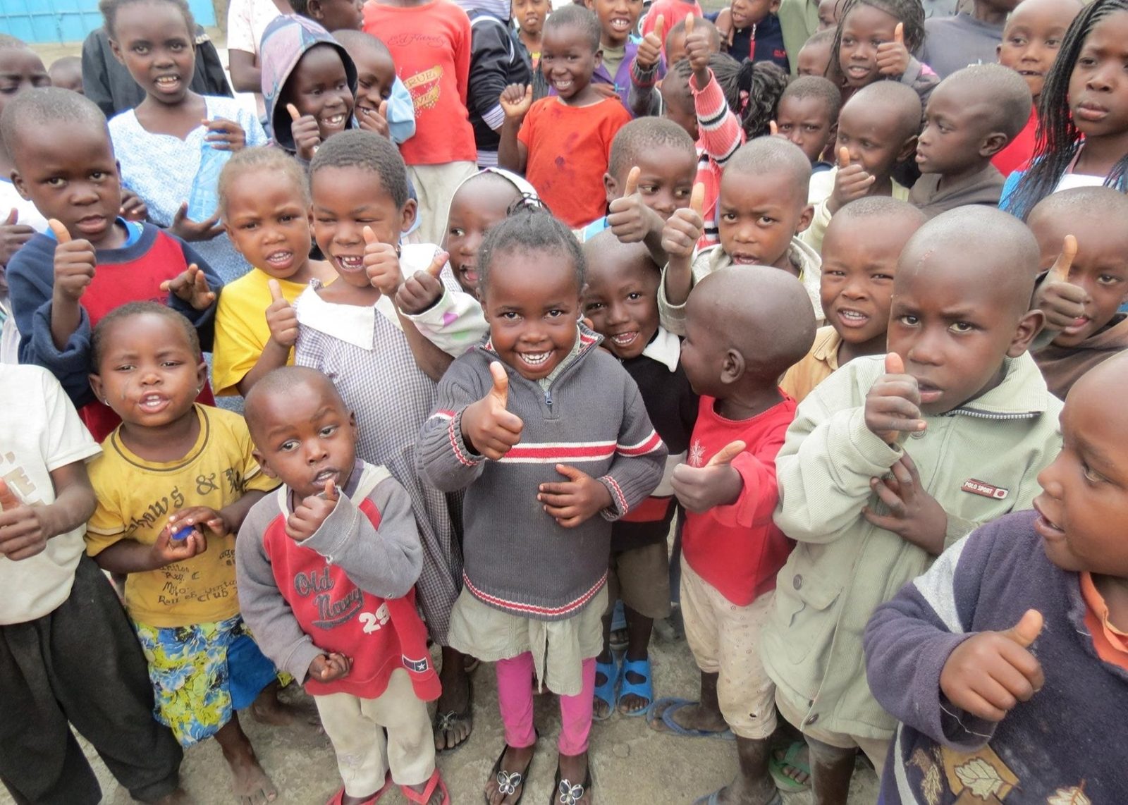 A large group of smiling children giving a thumbs-up to the camera
